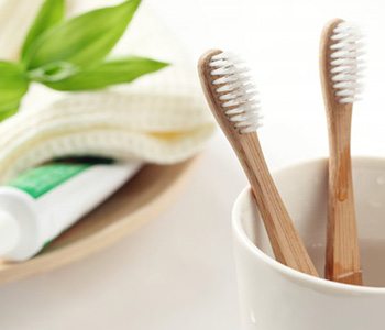 Two bamboo toothbrushes and a tube of toothpaste