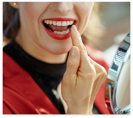 Woman with red lipstick looking at her teeth in mirror