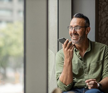 Man with glasses smiling while talking on phone