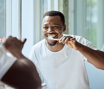 Man smiling while brushing his teeth