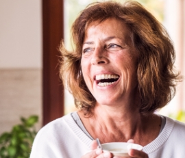 Smiling older woman holding a white coffee mug