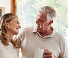 Man and woman smiling at each other with white coffee mugs