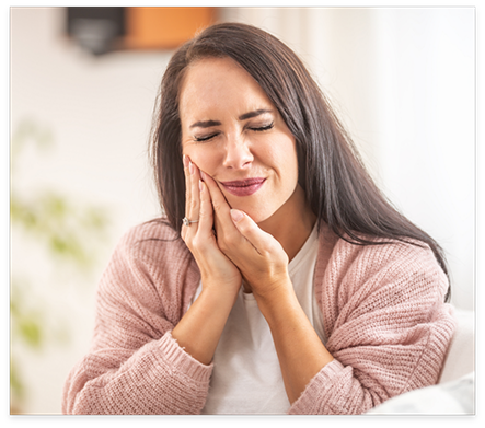 Wincing woman holding her cheek in pain