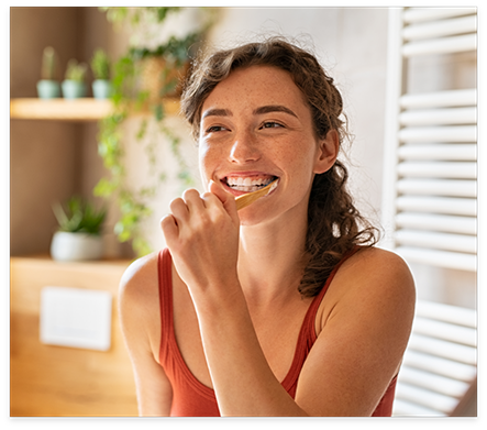 Young woman smiling while brushing her teeth