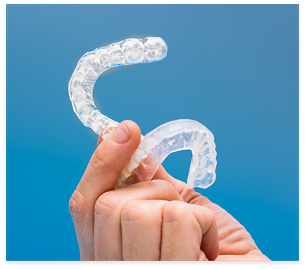 Hand holding two clear nightguards