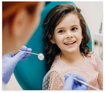 Young girl in dental chair smiling at her dentist