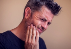 Man wincing and holding his jaw in pain