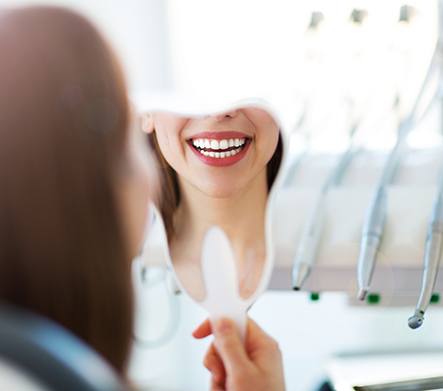 Woman holding mirror and smiling with brighter teeth
