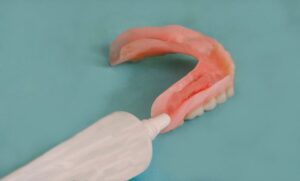 Person using adhesive cream on their dentures
